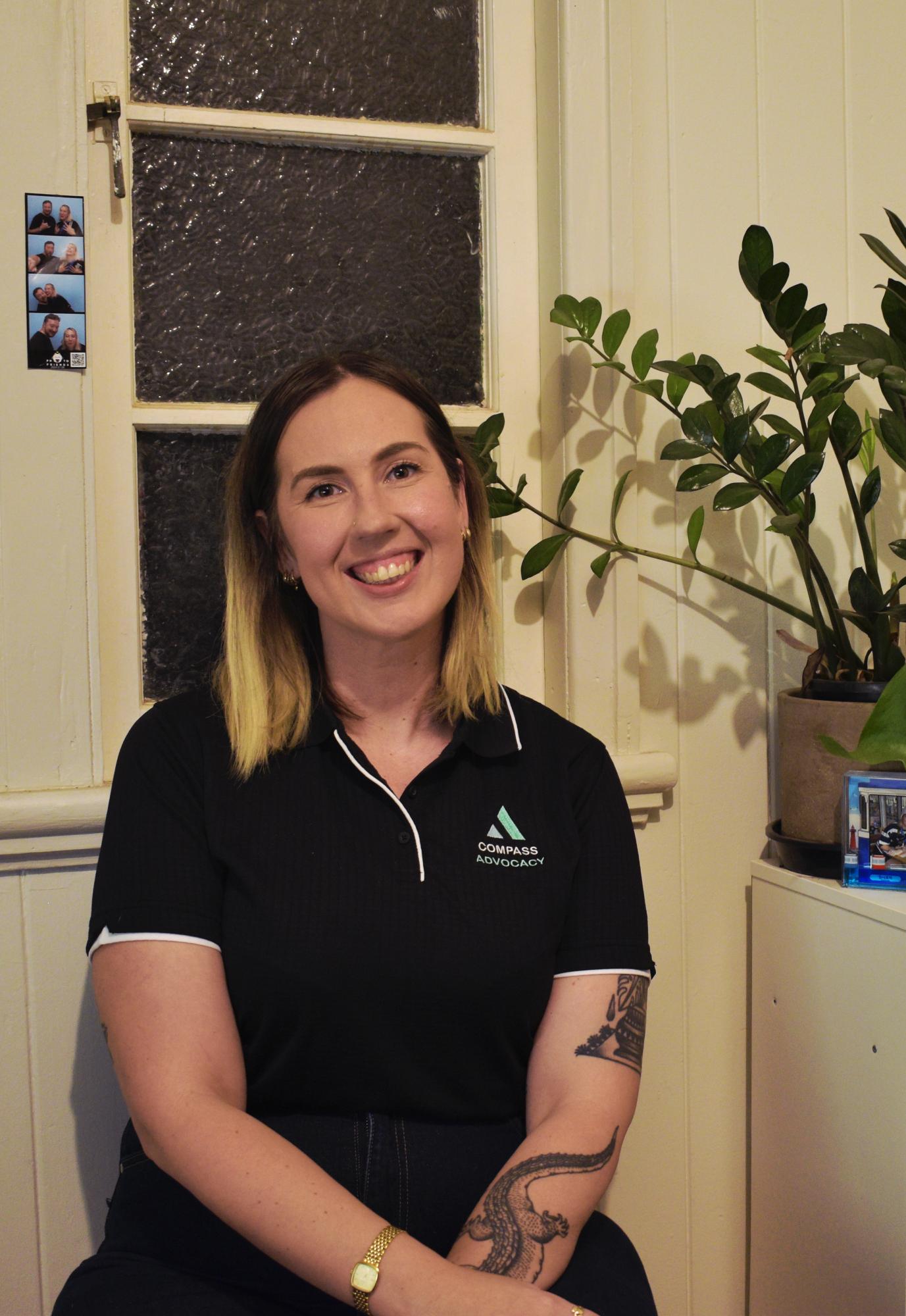 Charlotte Gawthorne, Principal Consultant, seated in the COMPASS Advocacy polo and smiling at the camera