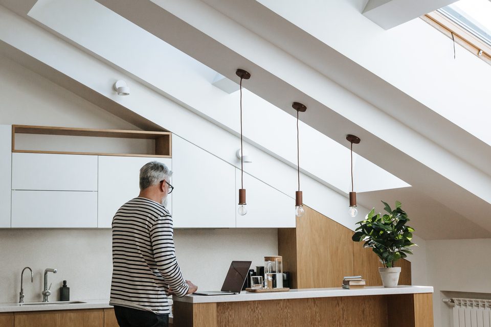 A man working at a laptop at a kitchen bench